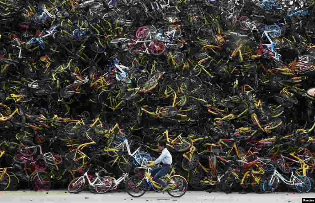 បុរស​ម្នាក់​ជិះ​កង់​មួយ​ឆ្លង​កាត់​គំនរ​កង់​ជាច្រើន​នៅ​ Xiamen ខេត្ត Fujian ប្រទេស​ចិន។