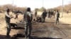 FILE - In this photo taken March 21, 2013, Malian soldiers stand around the debris left after a jihadist suicide bomber blew himself up at a Malian army checkpoint near the airport in Timbuktu, Mali.