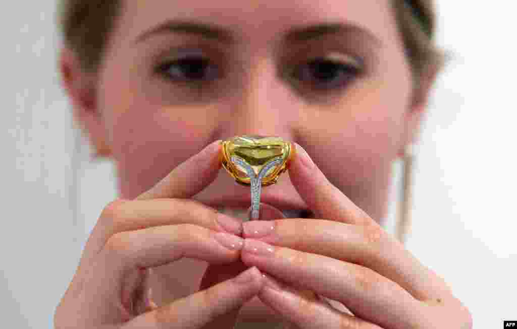 Seorang karyawati Sotheby berpose dengan &quot;Graff Vivid Yellow&quot; 100.09 karat - sebuah berlian kuning yang langka dalam ukuran tesebut, di London menjelang lelang seni New York untuk karya seni kontemporer, impresionis dan modern. &nbsp;