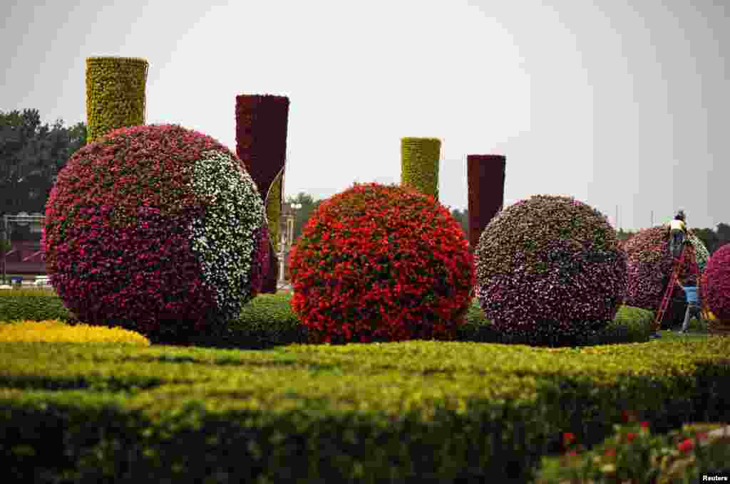 Workers put final touches on decorations made of flowers at Tiananmen Square in Beijing, China