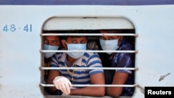 Migrant workers, who were stranded in the western state of Rajasthan due to a coronavirus lockdown, look out from the window of a train upon their arrival in their home state of eastern West Bengal, India.