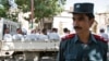 An Afghan police officer stands guard in front of a truck carrying Afghan prisoners on their way to court in Herat, western Afghanistan, August 16, 2009.