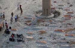 Policemen stand next to the bodies buried in shallow graves on the banks of Ganges river in Prayagraj, India, May 15, 2021. (AP)