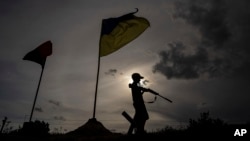 11岁的马克西姆在乌克兰哈尔科夫州的一条公路的自设检查站上端着塑料玩具枪。(2022年7月20日)