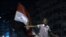 A youth shouts next to an Egyptian flag as the revolutionary youth of Egypt return to Tahrir to protest the outcome of the Egyptian presidential election, Cairo, Egypt, May 28, 2012.