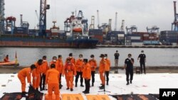 Tim SAR meletakkan kantong jenazah berisi jenazah yang ditemukan dari lokasi jatuhnya penerbangan Sriwijaya Air SJ182 di Jakarta pada 10 Januari 2021. (Foto: AFP)