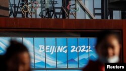 戴着口罩的行人在新一波冠状病毒病 (COVID-19) 爆发后出现在在2022 年冬奥会和冬残奥会北京组委会办公大楼附近。（路透社照片）