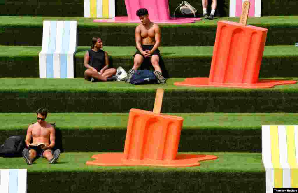 영국 런던 공원에 설치된 조각품들 사이에서 사람들이 여름을 즐기고 있다. 