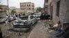 A man rests next to his car destroyed by Saudi-led airstrikes in Sana'a, Yemen, May 27, 2015.