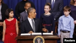 奥巴马总统1月16日在白宫签署控制枪支的行政命令时与身后的孩子交谈