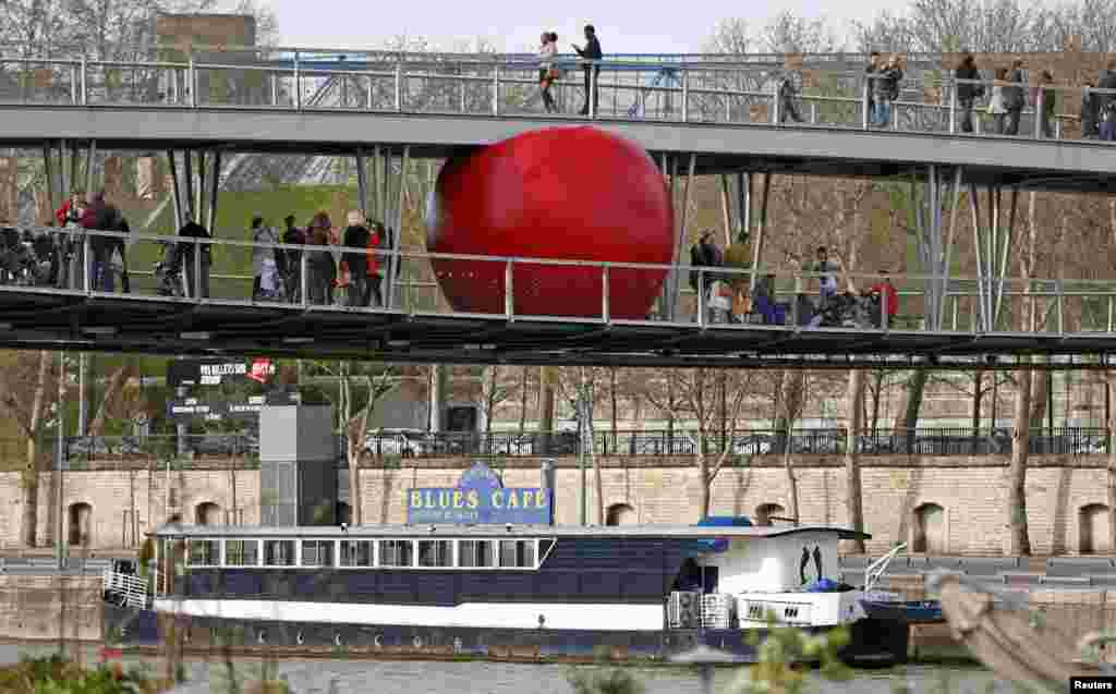 Bola merah besar dipasang di jembatan Simone de Beauvoir sebagai bagian dari karya seniman Kurt Perschke berjudul Bola Merah di Paris, Perancis. 