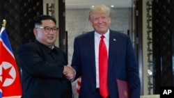 Le leader nord-coréen Kim Jong Un et le président américain Donald Trump se serrent la main après la signature d'un document à Capella, sur l'île de Sentosa, mardi 12 juin 2018 à Singapour. (AP Photo / Evan Vucci)