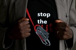 A man shows the logo of a T-shirt that reads "Stop the Cut" referring to Female Genital Mutilation (FGM) during a social event advocating against harmful practices such as FGM at the Imbirikani Girls High School in Imbirikani, Kenya, April 21, 2016
