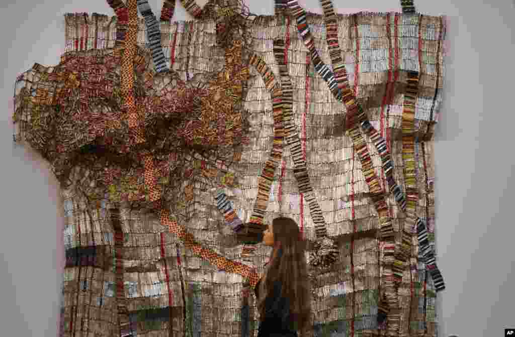 A Sotheby&#39;s employee looks at a sculpture created by El Anatsui of Ghana at Sotheby&#39;s Modern and Contemporary African Art sale in London. The sculpture is estimated to fetch $810,000 to 1.06 million 650,000-850,000 pounds.