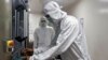 FILE - An employee in personal protective equipment (PPE) removes vials of AstraZeneca's COVISHIELD, COVID-19 vaccine from a visual inspection machine inside a lab at Serum Institute of India, Pune, Nov. 30, 2020.
