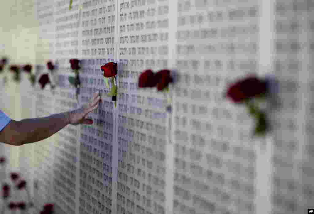 Seorang veteran menyentuh dinding di Latrun dekat Yerusalem, yang bertuliskan nama-nama tentara Israel yang tewas selama lebih dari satu abad konflik antara Yahudi dan Arab.