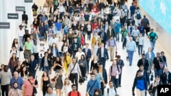 FILE - FILE - In this June 21, 2019, file photo commuters walk through a corridor in the World Trade Center Transportation Hub in New York. 