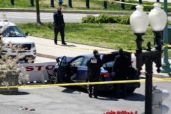 U.S. Capitol Police officers stand near a car that crashed into a barricade on Capitol Hill in Washington, April 2, 2021.