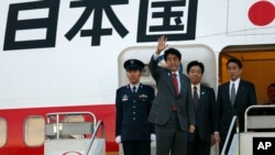 Perdana Menteri Jepang Shinzo Abe (dua dari kiri) melambaikan tangannya sesaat sebelum memasuki pesawatnya di bandara Internasional Haneda International Airport di Tokyo (21/2). Abe bertolak menuju Washington DC dan dijadwalkan akan bertemu dengan Presiden Obama Jumat, 22 Februari 2013.