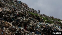 A man walks on waste at a dumping site as locals from a village near the site protest against garbage being dumped in their area by blocking garbage trucks from reaching the dumping site at the outside of Kathmandu, Nepal on June 8, 2022. (REUTERS/Navesh Chitrakar)