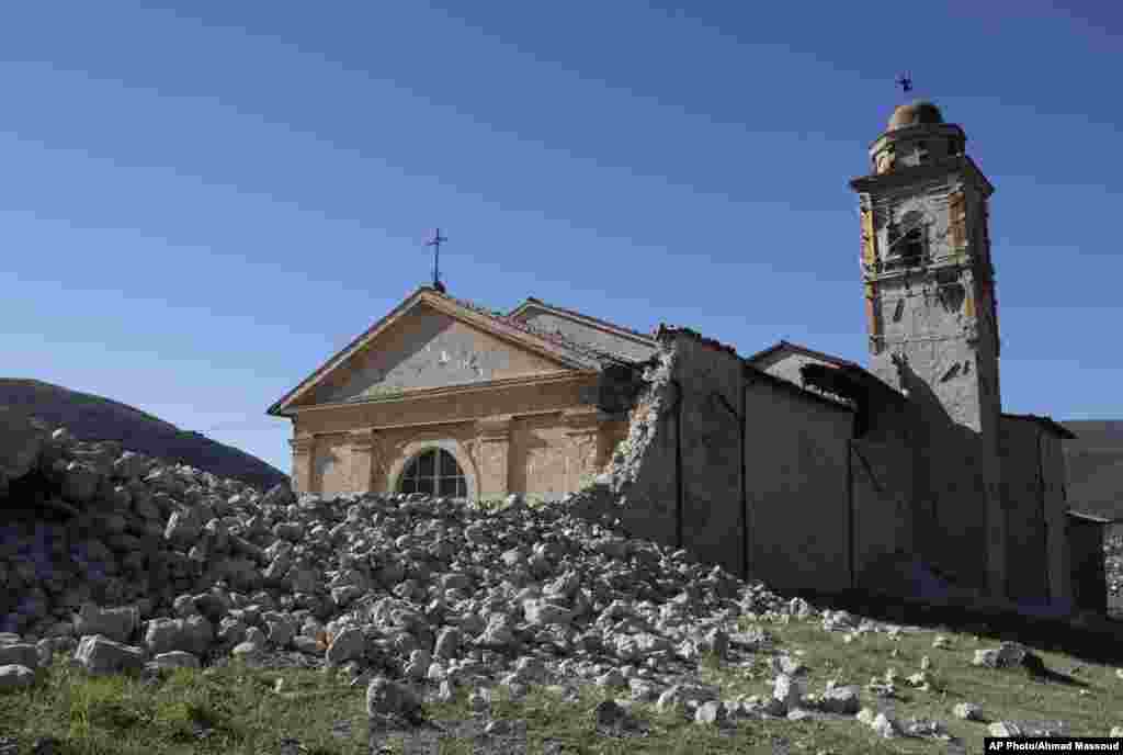Menara Gereja Madonna degli Angeli masih kokoh berdiri di tengah puing-puing bangunan yang hancur akibat gempa di dekat Norcia, Italia tengah (30/10).&nbsp;(AP/Gregorio Borgia)