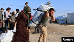 Syrian displaced families, who fled violence after the Turkish offensive in Syria, receive aid in Bardarash refugee camp on the outskirts of Dohuk, Iraq Oct. 22, 2019.