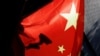 FILE — A surveillance camera is silhouetted behind a Chinese national flag in Beijing, China, Nov. 3, 2022.