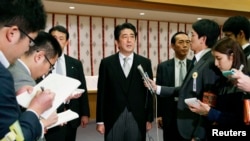 日本首相安倍晋三（中）在参拜东京靖国神社后与媒体见面。（2013年12月26日）