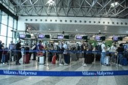 Passengers line up to at the check-in gates, at the Milan Malpensa airport, June 15, 2020.