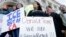 Protesters hold signs as they listen to speakers at a rally outside City Hall in San Francisco, Jan. 25, 2017.