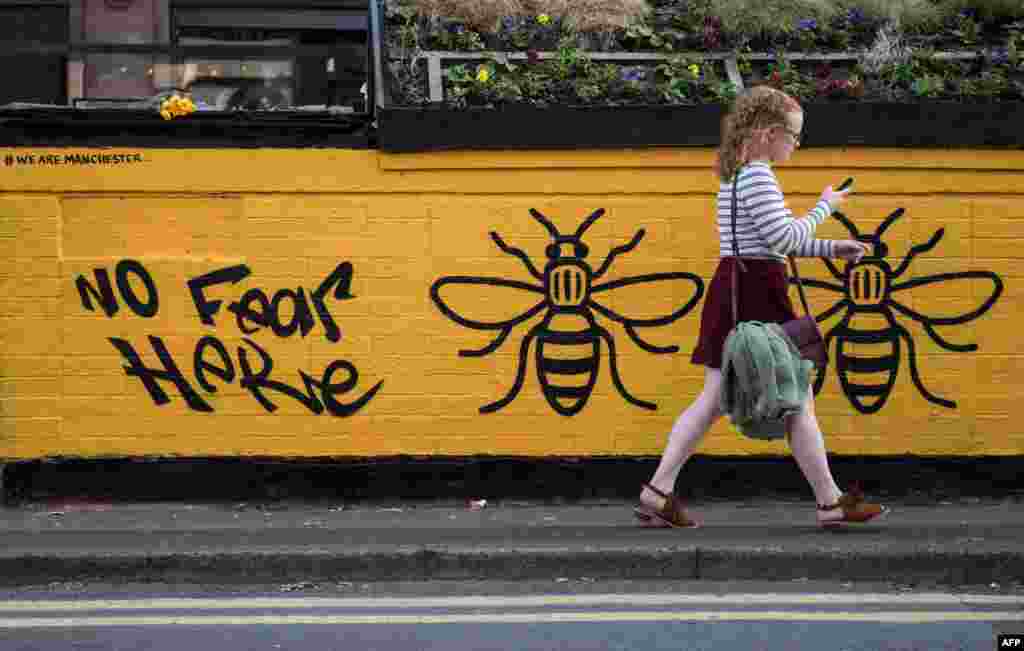 Seorang remaja perempuan melewati lukisan mural yang dibuat seniman jalanan pasca serangan teror Manchester di Lapangan Stevenson, Manchester, Inggris.