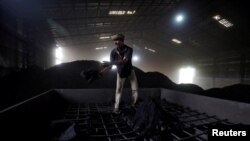 FILE - A laborer works inside a coal yard on the outskirts of Ahmedabad, India, April 6, 2017.