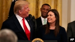 President Donald Trump welcomes White House press secretary Sarah Sanders to the stage as he pauses from speaking about second chance hiring to publicly thank the outgoing press secretary in the East Room of the White House, June 13, 2019, in Washington.