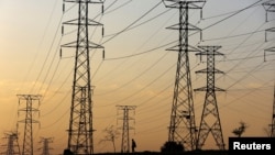 资料照：2023年1月16日，在南非索韦托奥兰多，一名男子在南非Eskom电力公司因燃煤电厂老化而频繁停电的电力塔下行走。