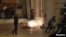 Wapalestina wakijihami kutokana na maguruneti ya polisi wa Israeli katika ghasia nje ya msikiti wa Al-Aqsa. 