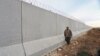 A Kurdish People's Protection Units (YPG) fighter walks near a wall, which activists said was put up by Turkish authorities, on the Syria-Turkish border in the western countryside of Ras al-Ain, Syria, Jan. 29, 2016.