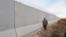 A Kurdish People's Protection Units (YPG) fighter walks near a wall, which activists said was put up by Turkish authorities, on the Syria-Turkish border in the western countryside of Ras al-Ain, Syria, Jan. 29, 2016.