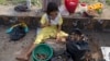 A girl uses a hammer to crack open shells for edible seeds to sell as snacks in Yangon, Myanmar, Nov. 1, 2018. A United Nations report says some 486 million people are malnourished in Asia and the Pacific, and progress in alleviating hunger is stalling.