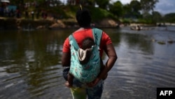 រូបឯកសារ៖ ជនចំណាកស្រុក​រួមជាមួយ​ទារក​ឆ្លងកាត់​ទន្លេ Chucunaque បន្ទាប់ពី​ធ្វើ​ដំណើរ​ថ្មើរ​ជើង​កាត់ព្រៃ​តំបន់ Darien Gap ក្នុង​ភូមិ Bajo Chiquito ខេត្ត Darien ប្រទេស​ប៉ាណាម៉ា កាលពី​ថ្ងៃទី១០ ខែកុម្ភៈ ឆ្នាំ២០២១។