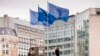 FILE - European Union flags flap in the wind as two gardeners work outside EU headquarters in Brussels, Sept. 11, 2019.