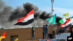 Smoke rises after pro-Iranian militiamen and their supporters set a fire in front of the U.S. embassy in Baghdad, Iraq, Jan. 1, 2020.