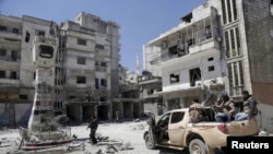 Pemberontak memeriksa lokasi yang hancur akibat serangan udara yang dilakukan oleh pasukan yang setia kepada Presiden Suriah Bashar al-Assad di kota Jisr al-Shughour, setelah para pemberontak menguasai wilayah tersebut, 26 April 2015.