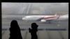 FILE - A woman and a girl look at a Malaysia Airlines plane on the tarmac of Kuala Lumpur International Airport.