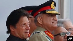 In this March 23, 2019 photo, Pakistan's Army Chief Gen. Qamar Javed Bajwa, center, watches a parade with Prime Minister Imran Khan, left, and President Arif Alvi, in Islamabad, Pakistan. Khan is keeping his powerful army chief in place for another…