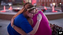 Christina Walls, left, and Diana Lennon embrace during a candlelight vigil July 24, 2015, to honor victims killed a day earlier in a movie theater in Lafayette, Louisiana. 