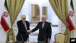 Menteri Luar Negeri Iran Mohammad Javad Zarif (kanan) berjabat tangan dengan utusan PBB-Liga Arab untuk Suriah Lakhdar Brahimi pada konferensi pers di Tehran (26/10).