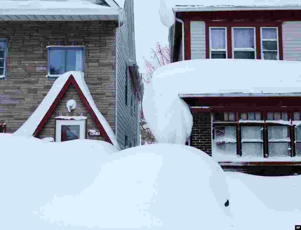 Snow is piled high on a vehicle and on houses in the south Buffalo area, Nov. 20, 2014, in Buffalo, N.Y.