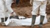 FILE - Forensic experts examine human remains at a mass grave in the village of Tomasica, near the Bosnian town of Prijedor, Oct. 31, 2013. Exhumations are currently underway at Koricani Cliffs, a nearby site.