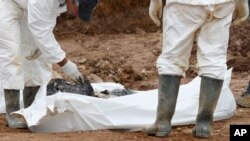 FILE - Forensic experts examine human remains at a mass grave in the village of Tomasica, near the Bosnian town of Prijedor, Oct. 31, 2013. Exhumations are currently underway at Koricani Cliffs, a nearby site.