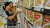 A sales assistant helps a customer to select Dumex milk powder at a market in Hefei, China, August 5, 2013. 